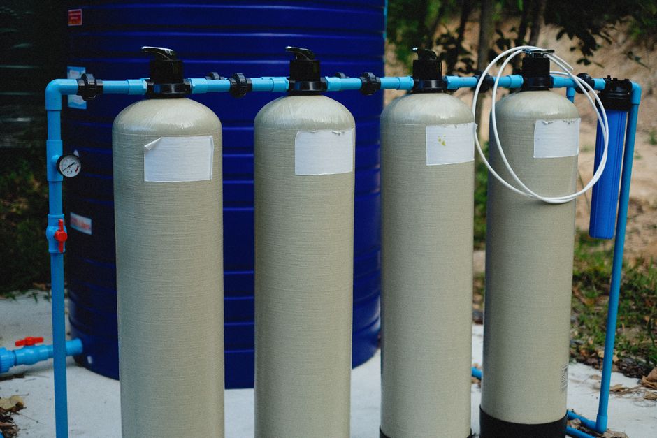 An above-ground polyethylene water storage tank wrapped in foam insulation and a reflective outer cover, inside a wooden enclosure.