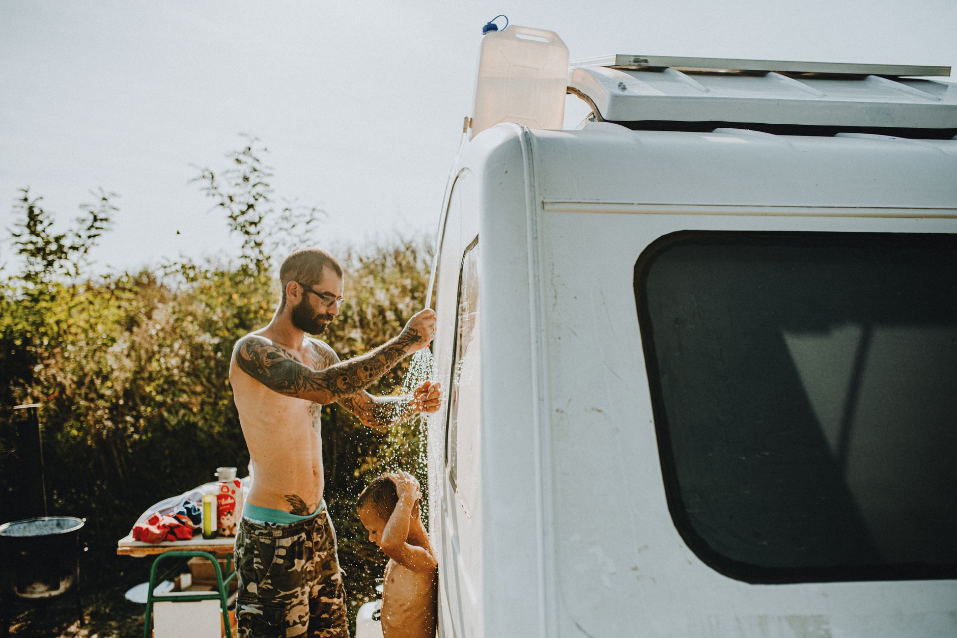 Portable tankless water heater mounted outdoors near a propane tank and shower hose