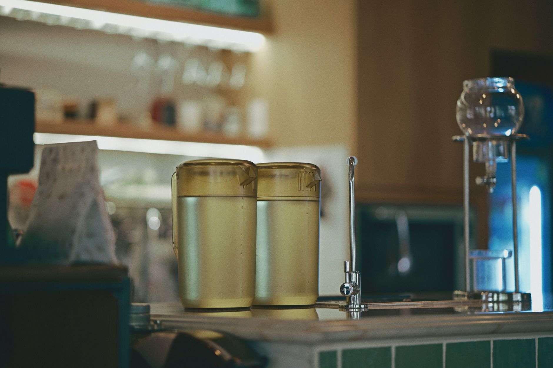 Countertop gravity water filter system with two chambers, clean water pouring into glass